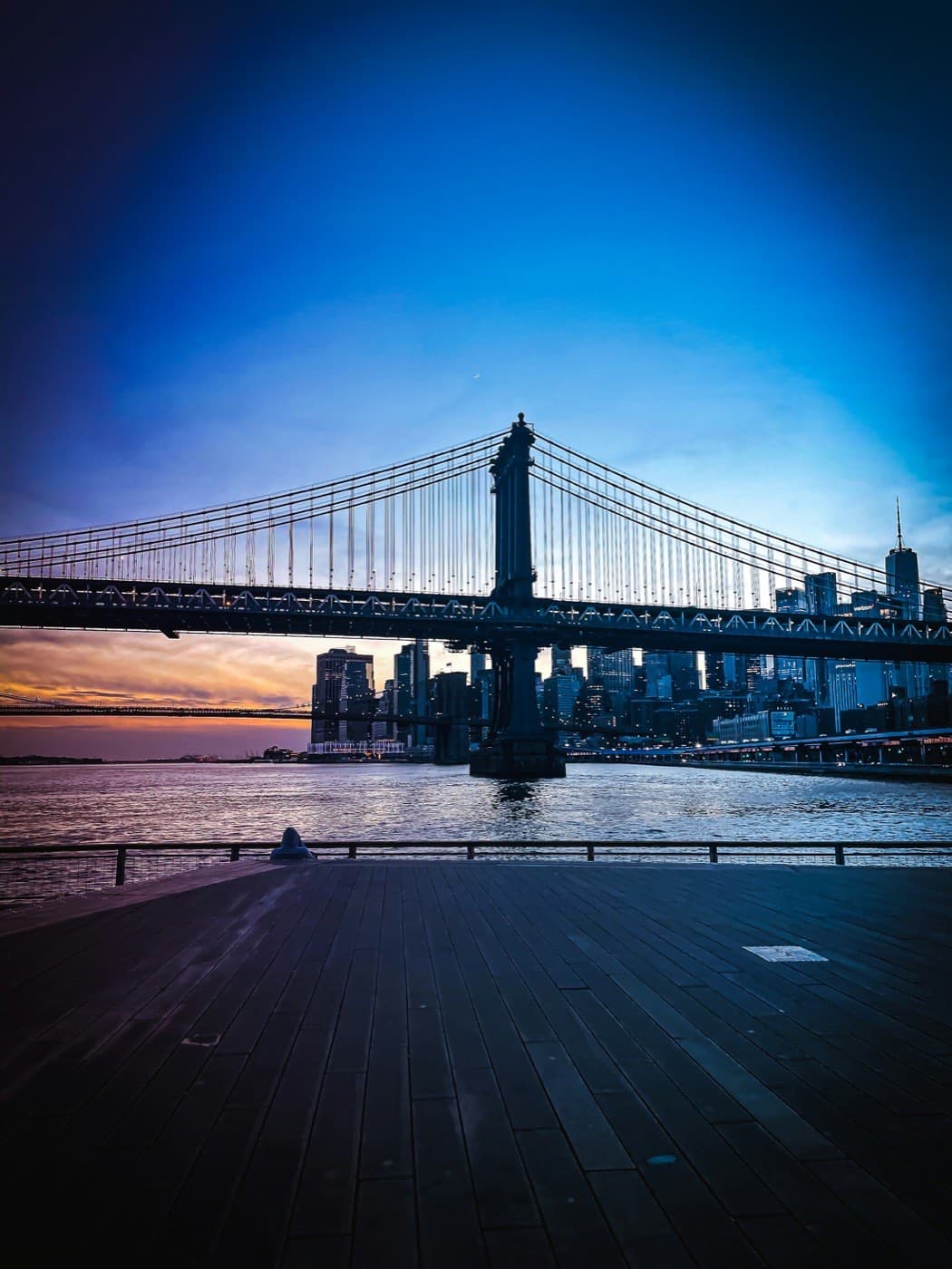 Pier 35 East River deck at sunset with Manhattan Bridge and Lower Manhattan skyline